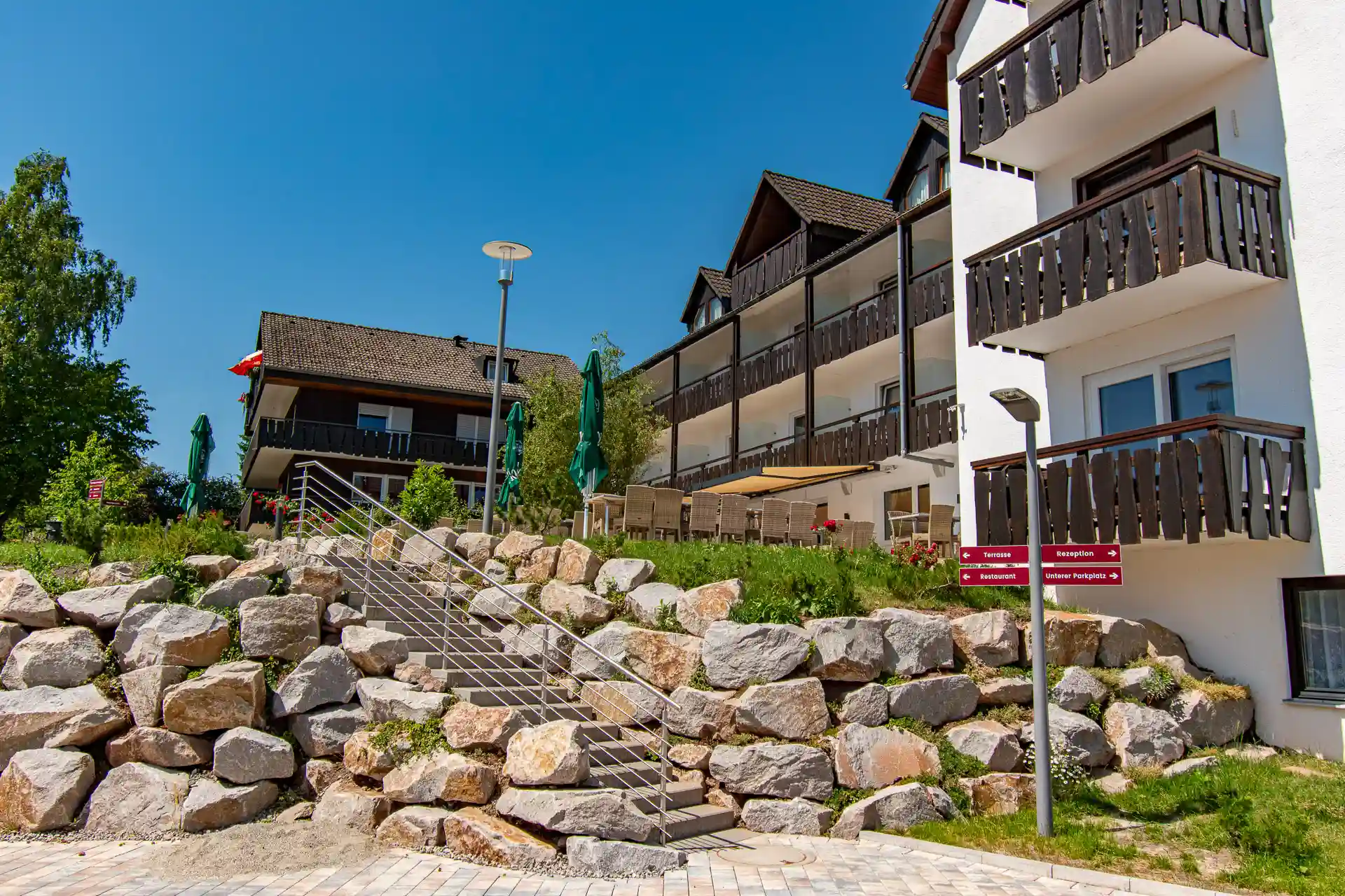Außenansicht des Wellnesshotels Hohenrodt mit dem Hotelgebäude, einem Parkplatz und dem einladenden Treppenaufgang, der zum Eingang führt