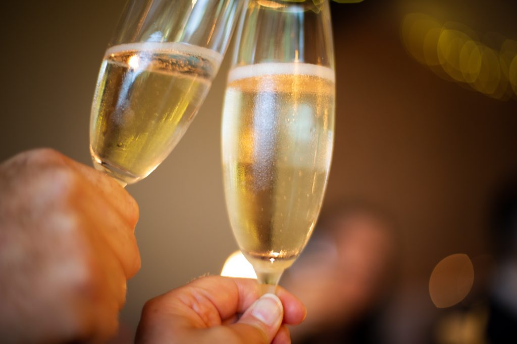 Zwei Gläser Sekt, die zum Anstoßen erhoben werden