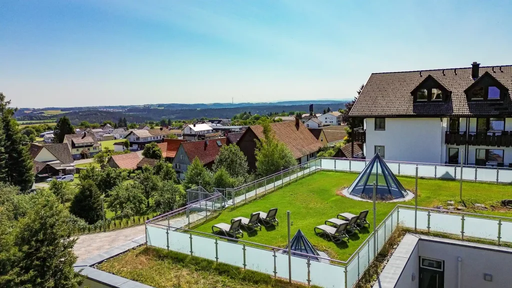 Luftaufnahme des Wellnesshotels Hohenrodt mit Hotelgebäude, gepflegter Liegewiese und Panoramablick auf die umliegende Natur.