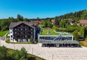 Luftaufnahme des Wellnesshotels Hohenrodt, modernes Hauptgebäude mit lichtdurchflutetem Wellnessanbau inmitten natürlicher Waldlandschaft