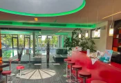 Stimmungsvolle Wellness-Rezeption mit grüner LED-Beleuchtung und stilvollem Blick auf den angrenzenden Poolbereich