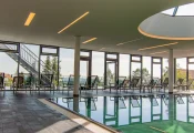 Entspannte Atmosphäre im Poolbereich mit bequemen Relaxliegen vor großzügiger Fensterfront und natürlichem Lichteinfall